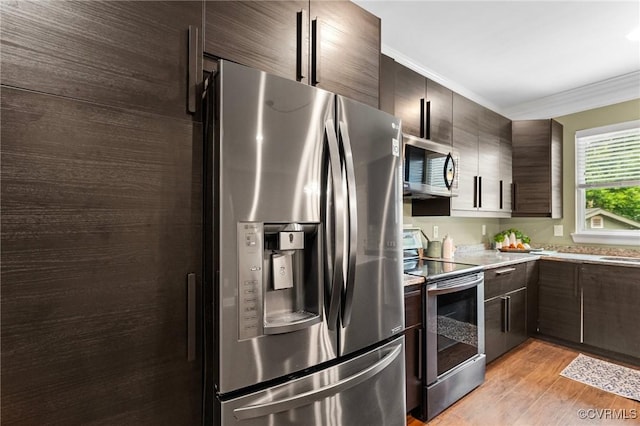 3104 1st Ave, Richmond, VA 23222 - kitchen featuring appliances with stainless steel finishes, crown molding, dark brown cabinets, light wood-type flooring, and modern cabinets