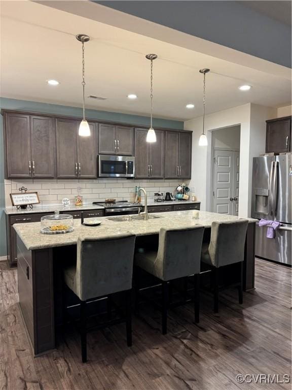 6948 Desert Candle Dr, Moseley, VA 23120 - kitchen featuring appliances with stainless steel finishes, dark wood finished floors, a breakfast bar, decorative backsplash, and light stone counters