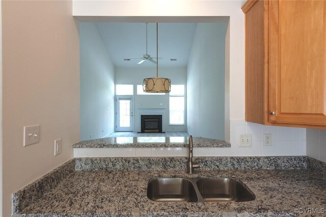10504 Bishops Gate Dr, Glen Allen, VA 23059 - kitchen featuring a sink, a ceiling fan, decorative backsplash, stone counters, and a fireplace
