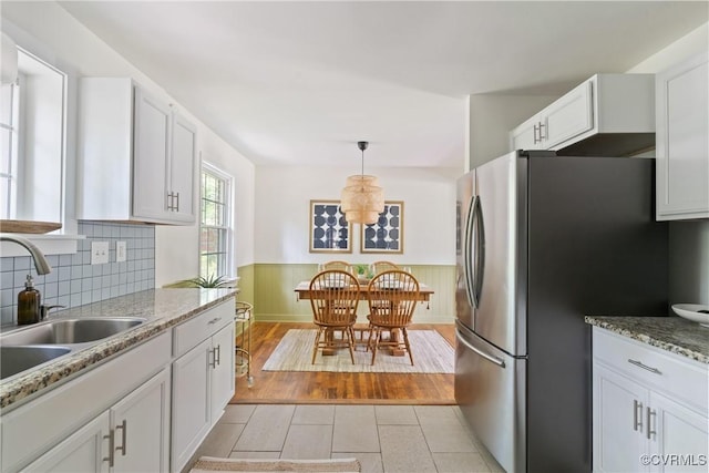 6405 Hagueman Dr, Richmond, VA 23225 - kitchen featuring freestanding refrigerator, a sink, a wainscoted wall, and white cabinetry