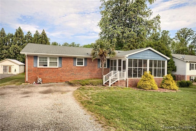 7486 Roaring Springs Rd, Gloucester, VA 23062 - view of front facade featuring a sunroom, brick siding, gravel driveway, and a front lawn