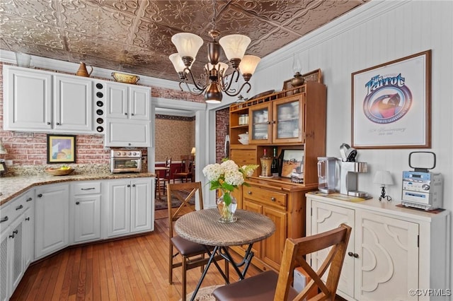 1520 Bellevue Ave, Richmond, VA 23227 - kitchen with an ornate ceiling, a chandelier, light wood-type flooring, white cabinetry, and light stone counters