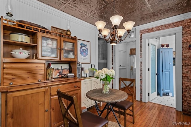 1520 Bellevue Ave, Richmond, VA 23227 - dining area featuring a chandelier, light wood finished floors, an ornate ceiling, and brick wall
