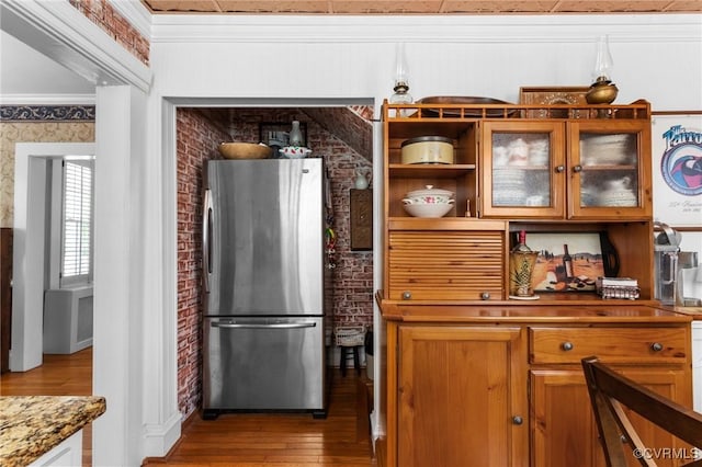 1520 Bellevue Ave, Richmond, VA 23227 - kitchen with freestanding refrigerator, wood finished floors, ornamental molding, brick wall, and glass insert cabinets