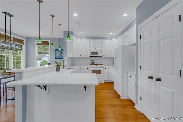 118 Old Field Rd, Irvington, VA 22480 - kitchen featuring white appliances, a peninsula, a sink, light wood finished floors, and a breakfast bar area