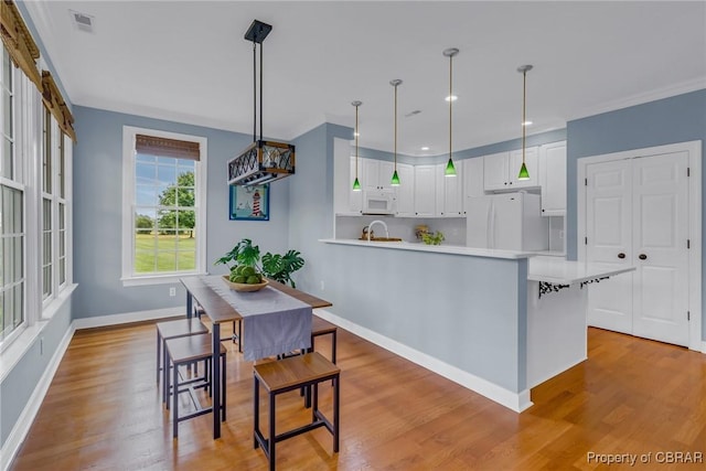 118 Old Field Rd, Irvington, VA 22480 - kitchen featuring white appliances, light countertops, light wood-style flooring, white cabinets, and a peninsula