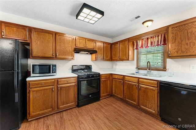 6402 Willow Landing Way, Chester, VA 23831 - kitchen featuring black appliances, a sink, under cabinet range hood, wood finished floors, and a textured ceiling