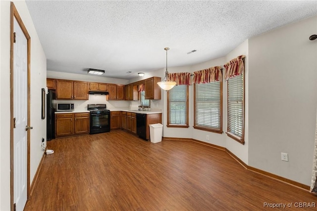 6402 Willow Landing Way, Chester, VA 23831 - kitchen with black appliances, under cabinet range hood, light countertops, dark wood-type flooring, and brown cabinets