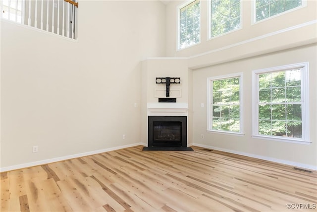 11830 Cedar Landing Ter, Chesterfield, VA 23831 - unfurnished living room featuring a towering ceiling, healthy amount of natural light, baseboards, wood finished floors, and a fireplace with flush hearth