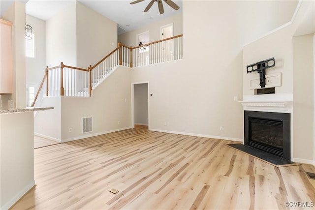 11830 Cedar Landing Ter, Chesterfield, VA 23831 - unfurnished living room featuring ceiling fan, a high ceiling, light wood-style floors, stairs, and a glass covered fireplace