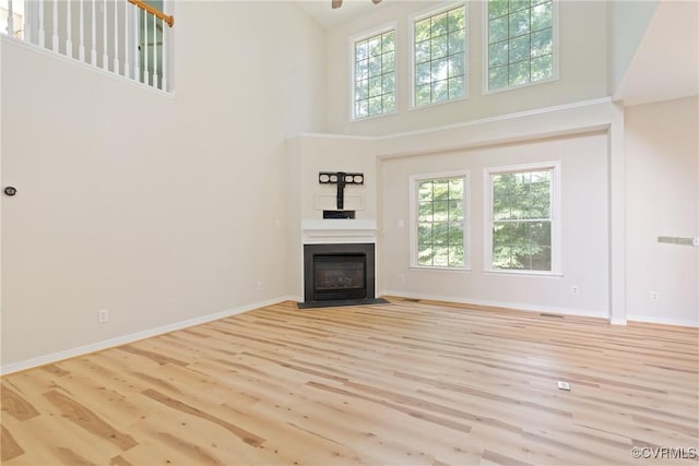 11830 Cedar Landing Ter, Chesterfield, VA 23831 - unfurnished living room featuring a towering ceiling, wood finished floors, a fireplace with flush hearth, and baseboards