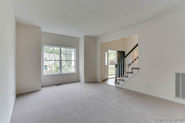 106 Haymaker Pl, Williamsburg, VA 23185 - unfurnished living room with healthy amount of natural light, carpet floors, stairs, and a textured ceiling