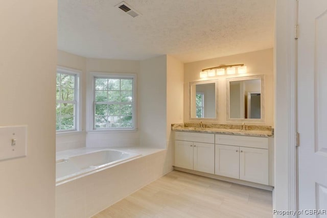 106 Haymaker Pl, Williamsburg, VA 23185 - bathroom with double vanity, a bath, and a textured ceiling