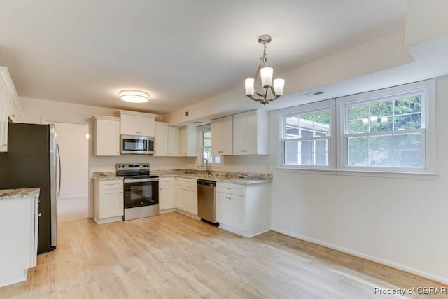 205 Captains Ct, Hampton, VA 23669 - kitchen featuring appliances with stainless steel finishes, light wood-style floors, white cabinets, a chandelier, and light stone countertops