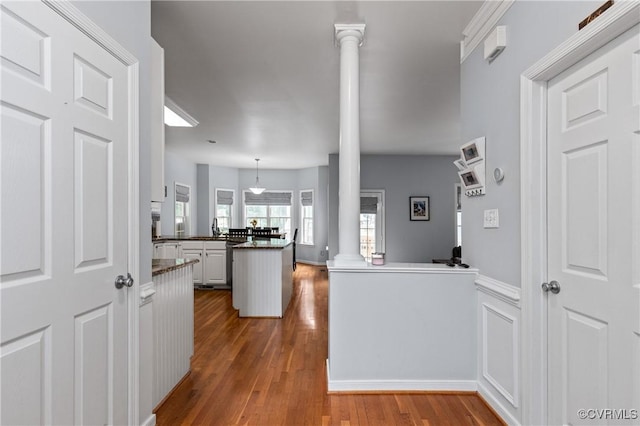8940 Kings Charter Dr, Hanover, VA 23116 - kitchen with ornate columns, wood finished floors, a peninsula, dark countertops, and wainscoting