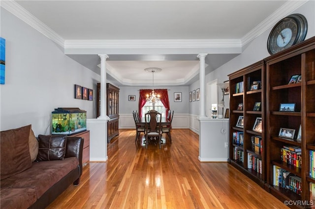 8940 Kings Charter Dr, Hanover, VA 23116 - dining room featuring decorative columns, light wood-style floors, a chandelier, crown molding, and a wainscoted wall