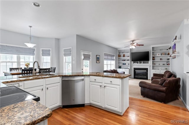 8940 Kings Charter Dr, Hanover, VA 23116 - kitchen with stainless steel dishwasher, a glass covered fireplace, a ceiling fan, white cabinets, and light wood-style flooring