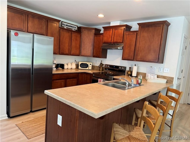 230 Roseneath Ave, Kilmarnock, VA 22482 - kitchen featuring appliances with stainless steel finishes, under cabinet range hood, a peninsula, a sink, and light wood-style flooring