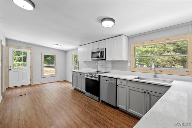 10780 Winchester Dr, Amelia Courthouse, VA 23002 - kitchen with appliances with stainless steel finishes, gray cabinets, wood finished floors, vaulted ceiling, and tasteful backsplash