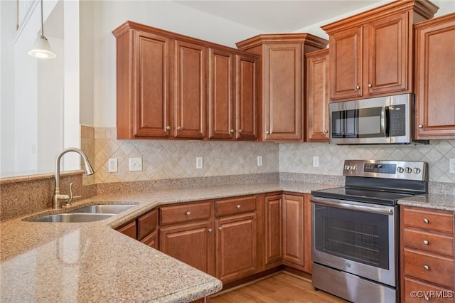 8156 Cool Summer Dr, Mechanicsville, VA 23111 - kitchen with stainless steel appliances, light stone counters, light wood finished floors, and brown cabinetry