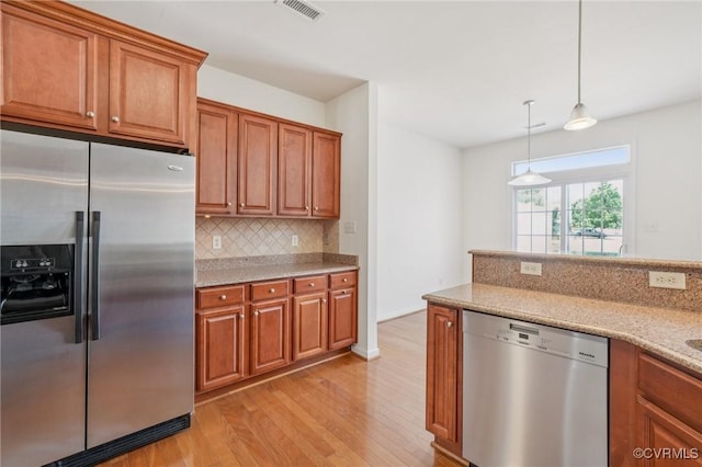 8156 Cool Summer Dr, Mechanicsville, VA 23111 - kitchen featuring appliances with stainless steel finishes, light wood-style flooring, brown cabinetry, decorative backsplash, and light stone counters