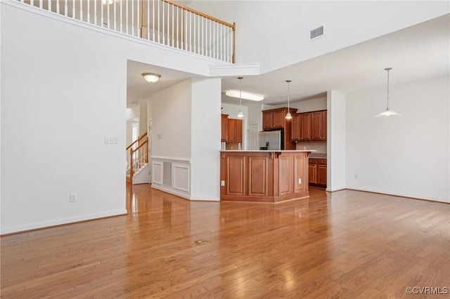 8156 Cool Summer Dr, Mechanicsville, VA 23111 - unfurnished living room with light wood-style flooring, a towering ceiling, and stairway