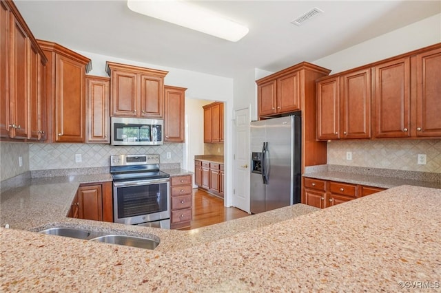 8156 Cool Summer Dr, Mechanicsville, VA 23111 - kitchen featuring appliances with stainless steel finishes, brown cabinets, light stone countertops, and backsplash