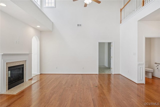 8156 Cool Summer Dr, Mechanicsville, VA 23111 - unfurnished living room featuring a towering ceiling, ceiling fan, wood finished floors, a fireplace, and arched walkways
