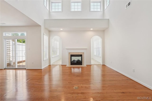 8156 Cool Summer Dr, Mechanicsville, VA 23111 - unfurnished living room featuring a towering ceiling, wood finished floors, healthy amount of natural light, a premium fireplace, and arched walkways
