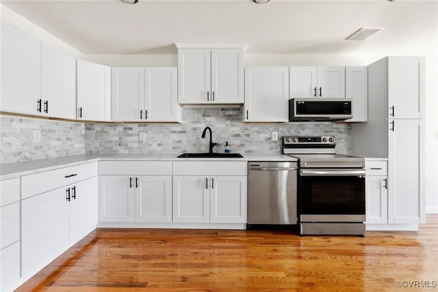1312 St Michaels Ln, Richmond, VA 23229 - kitchen with appliances with stainless steel finishes, light countertops, white cabinets, and decorative backsplash