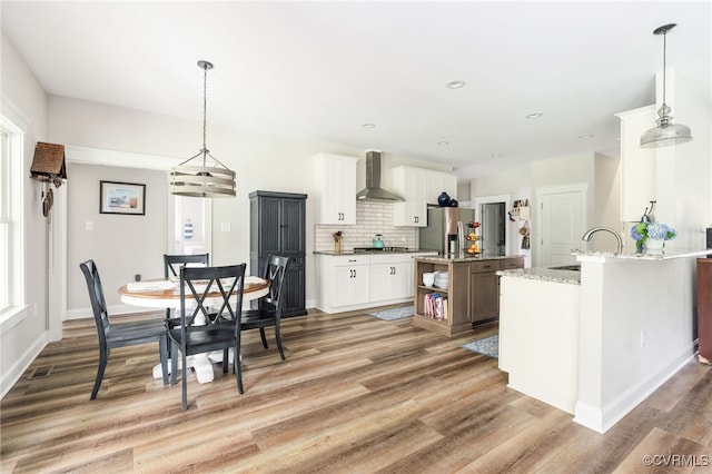 12025 Autumn Knoll Dr, Mechanicsville, VA 23116 - kitchen with wall chimney exhaust hood, light wood-style flooring, decorative backsplash, white cabinetry, and appliances with stainless steel finishes