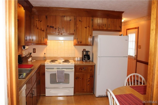 8318 Banshire Ct, Hanover, VA 23111 - kitchen with white appliances, under cabinet range hood, brown cabinets, and decorative backsplash
