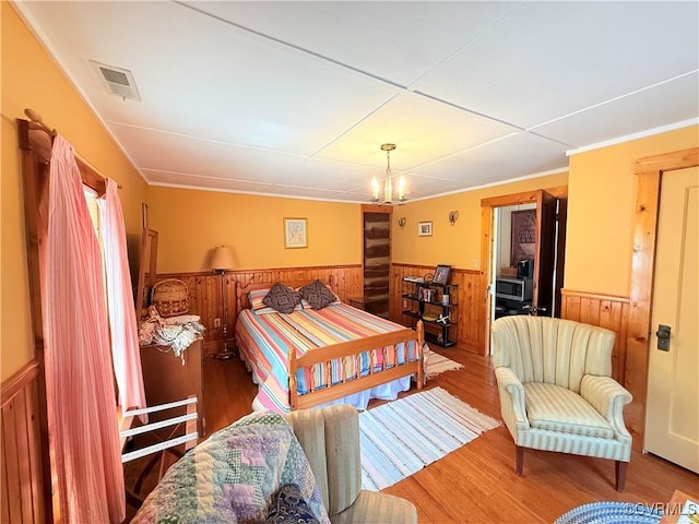12509 Sam Snead Hwy, Warm Springs, VA 24484 - bedroom featuring a wainscoted wall, wooden walls, wood finished floors, and a chandelier
