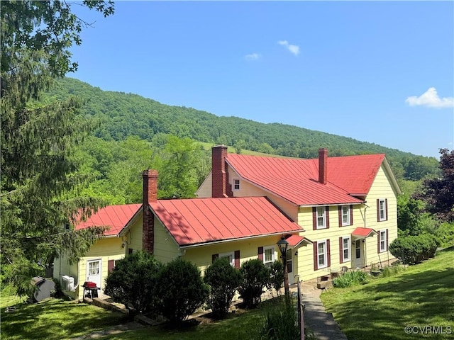 12509 Sam Snead Hwy, Warm Springs, VA 24484 - view of front facade featuring a chimney, a view of trees, a standing seam roof, metal roof, and a front lawn