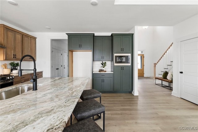 12731 Dell Hill Ct, Chester, VA 23831 - kitchen with a sink, a breakfast bar area, light stone countertops, light wood finished floors, and built in microwave