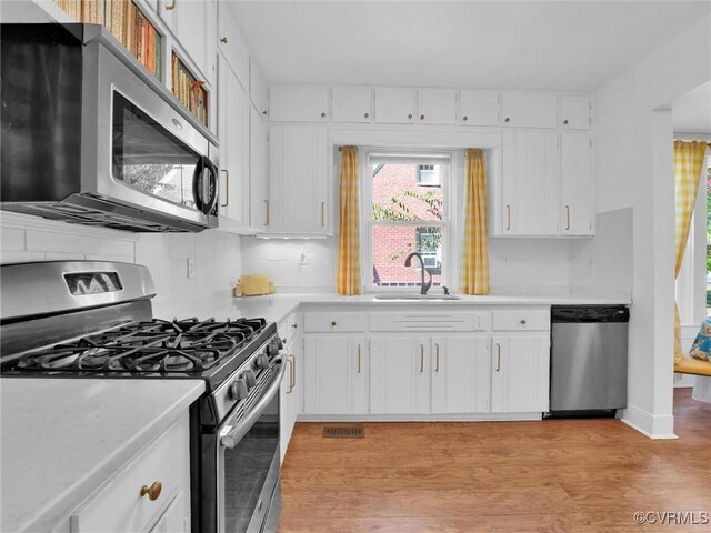 110 Gatewood Ave, Crewe, VA 23930 - kitchen with stainless steel appliances, a sink, light countertops, light wood-type flooring, and decorative backsplash
