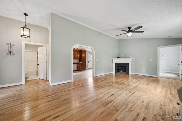 241 Deep Landing Rd, Tappahannock, VA 22560 - unfurnished living room with light wood-type flooring, ceiling fan, arched walkways, a fireplace, and a textured ceiling