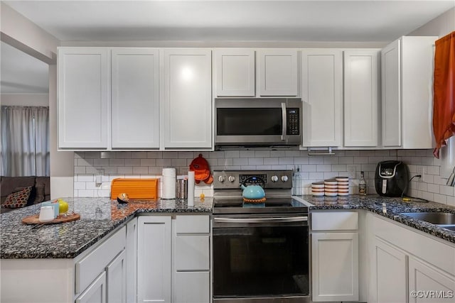 1939 Burks St, Petersburg, VA 23805 - kitchen with stainless steel appliances, white cabinets, a sink, tasteful backsplash, and dark stone counters
