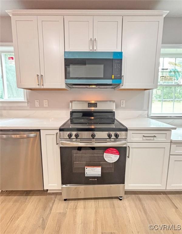 7906 Battlefield Park Rd, Henrico, VA 23231 - kitchen with stainless steel appliances, light wood-style floors, white cabinetry, and light countertops