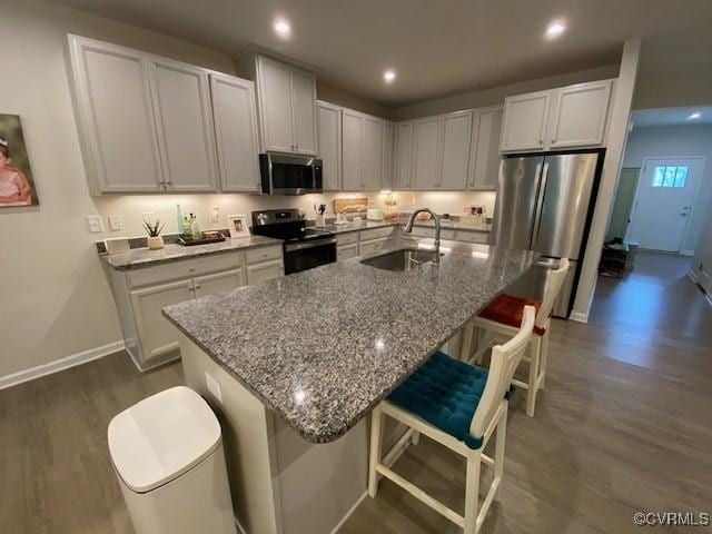 120 De La Warr Arch, Williamsburg, VA 23185 - kitchen with appliances with stainless steel finishes, dark wood-type flooring, light stone counters, a breakfast bar, and recessed lighting