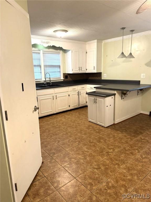 5404 Oak St, North Dinwiddie, VA 23803 - kitchen featuring a sink, dark countertops, decorative light fixtures, ornamental molding, and white cabinetry