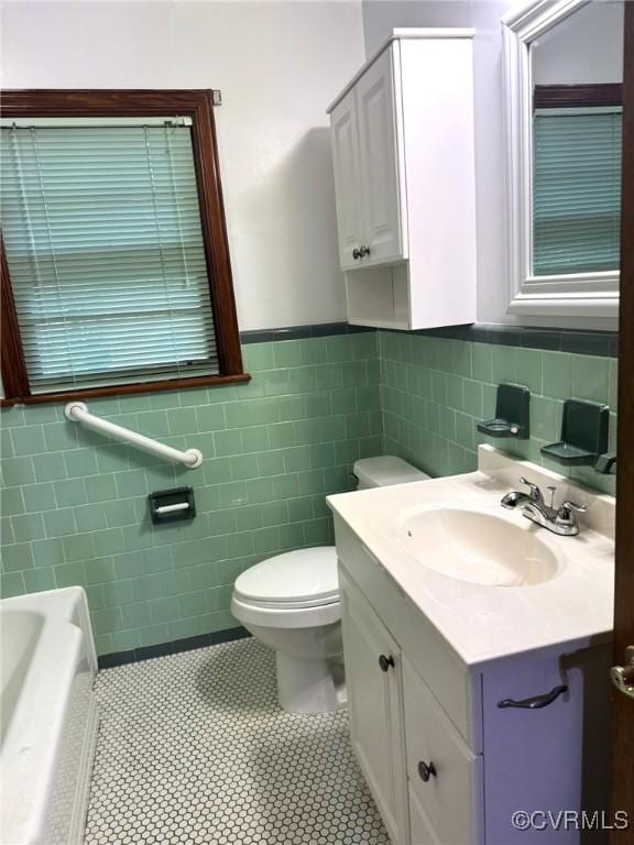 5404 Oak St, North Dinwiddie, VA 23803 - bathroom featuring tile walls, vanity, a tub to relax in, wainscoting, and tile patterned flooring