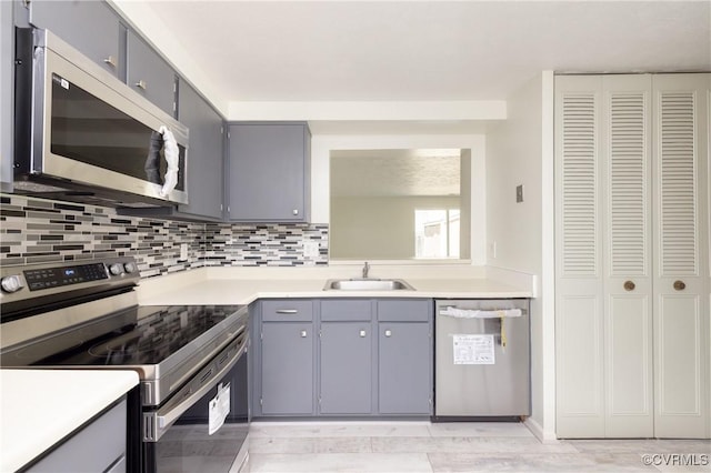 8406 Shannon Green Ct, Henrico, VA 23228 - kitchen featuring appliances with stainless steel finishes, gray cabinetry, backsplash, light countertops, and light wood-type flooring