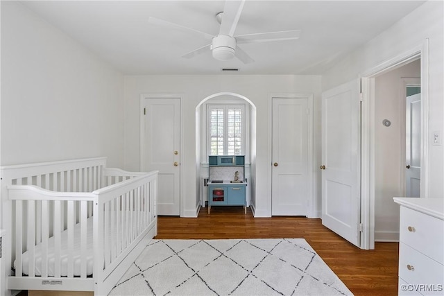 6502 W Franklin St, Henrico, VA 23226 - bedroom featuring arched walkways, wood finished floors, a ceiling fan, and a nursery area
