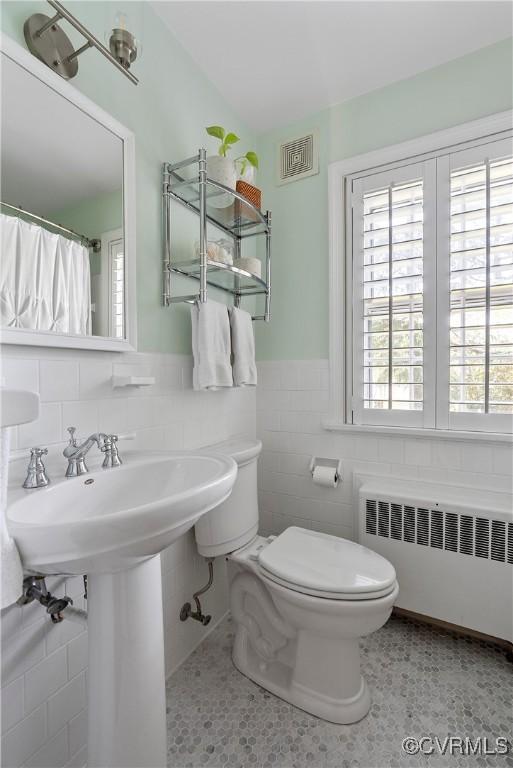 6502 W Franklin St, Henrico, VA 23226 - bathroom featuring radiator, tile walls, plenty of natural light, and a wainscoted wall