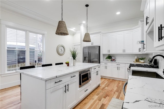 11 W 29th St, Richmond, VA 23225 - kitchen featuring appliances with stainless steel finishes, a kitchen island, crown molding, white cabinets, and pendant lighting