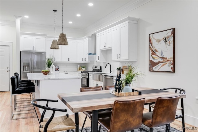 11 W 29th St, Richmond, VA 23225 - kitchen with appliances with stainless steel finishes, wall chimney exhaust hood, a center island, crown molding, and white cabinets