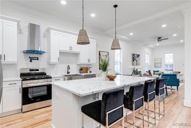 11 W 29th St, Richmond, VA 23225 - kitchen with appliances with stainless steel finishes, wall chimney exhaust hood, light wood-style flooring, a center island, and crown molding