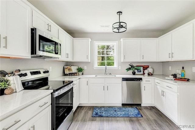 4100 Cralles Rd, Amelia, VA 23002 - kitchen featuring stainless steel appliances, white cabinets, light wood finished floors, and pendant lighting