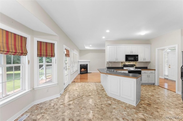13531 Butlers Rd, Amelia Courthouse, VA 23002 - kitchen with black microwave, white electric range oven, a lit fireplace, white cabinetry, and dark countertops